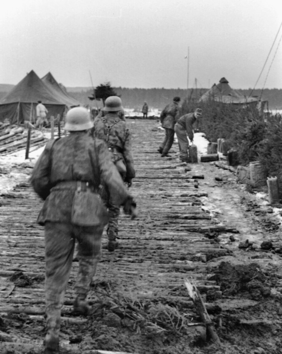 German soldiers loot an American camp that has been deserted and overrun. The Ardennes offensive was undertaken without an adequate supply of fuel, and soldiers in the background have located a number of jerry cans.