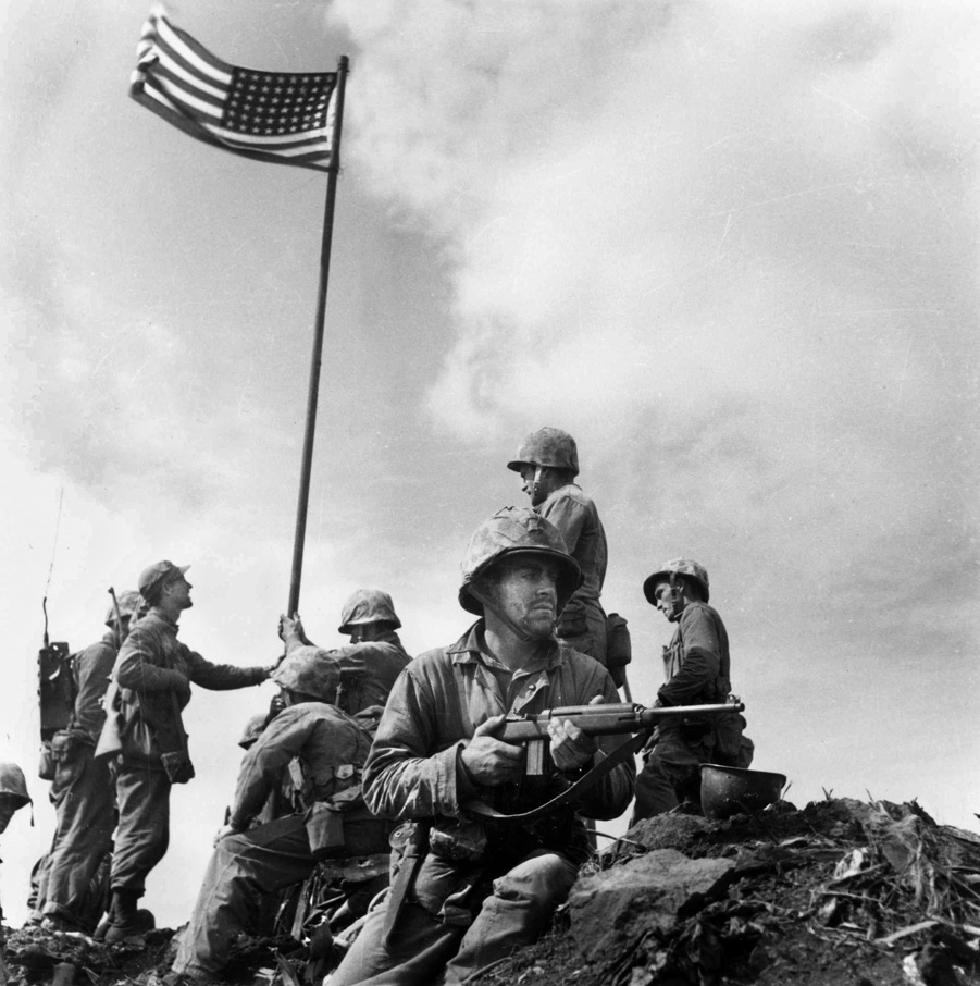 The first flag raising, with the smaller flag carried ashore by Company E, 2nd Battalion, 28th Marines, February 23, 1945.