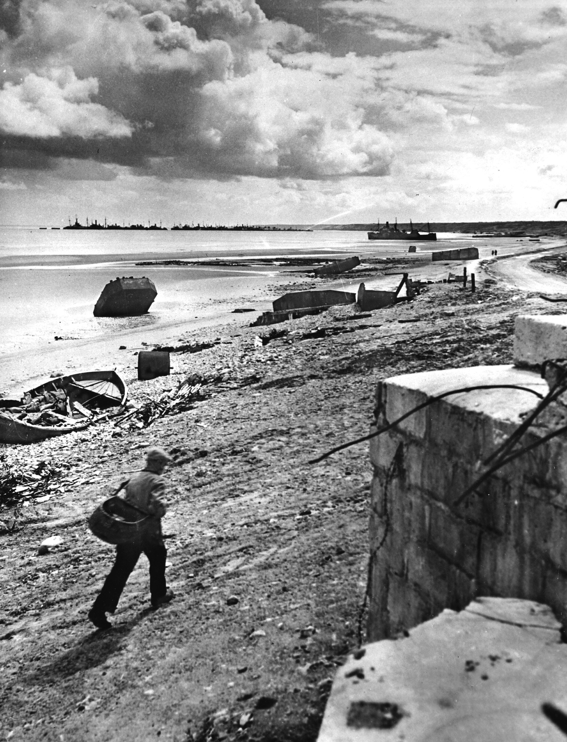 Frenchmen walks past a former German bunker on debris-strewn Omaha Beach near the Vierville exit where so much fierce fighting took place 12 months earlier.