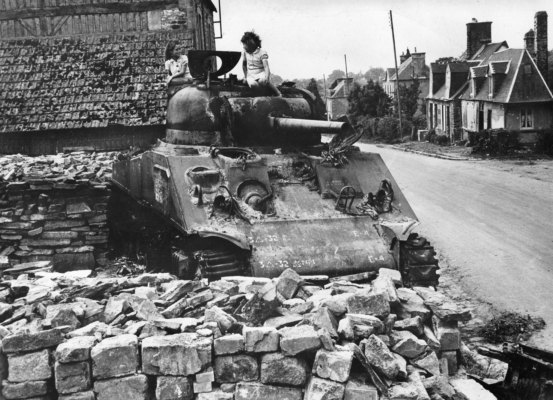 French children play atop a knocked-out Sherman tank that once belonged to the 3rd U.S. Armored Division.