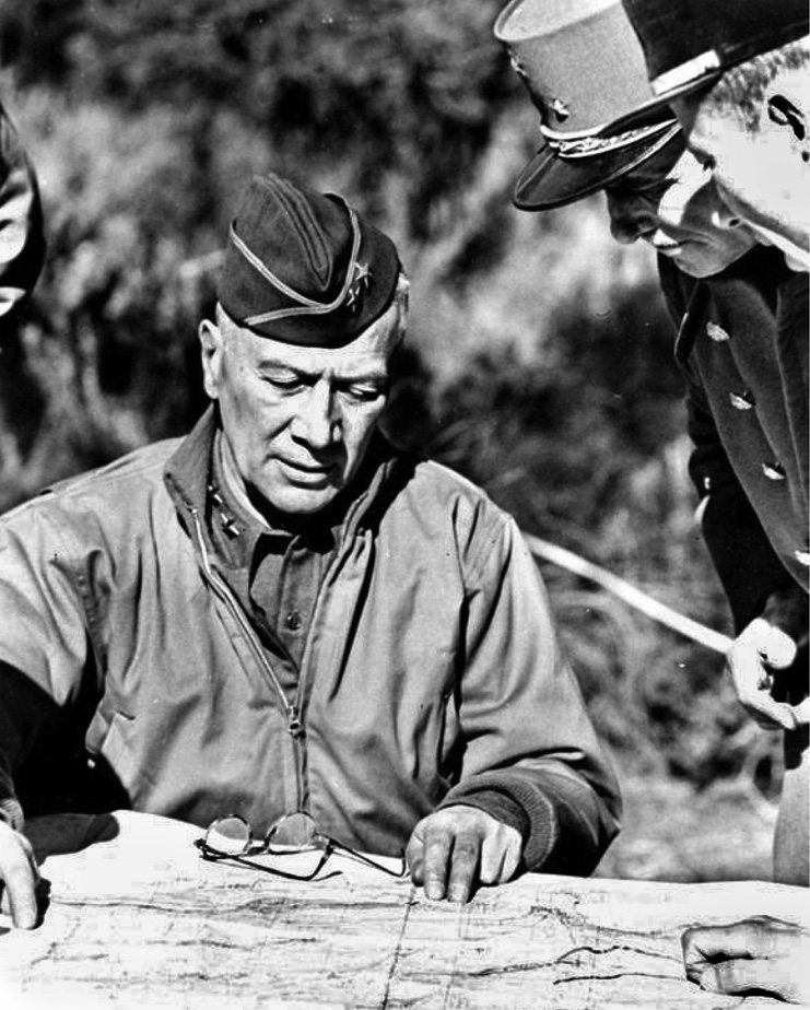 Major General Lloyd Fredendall converses with French officers in North Africa during a briefing.