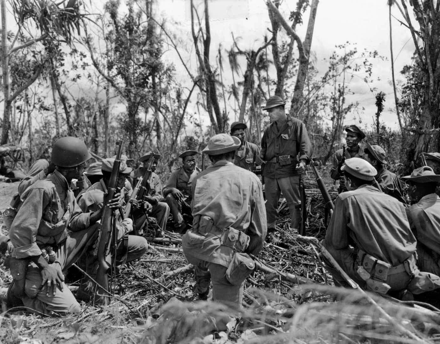 Members of the 1st Battalion, 24th Infantry are briefed by a white officer prior to heading out on a patrol in the Bougainville jungle, April 16, 1944.