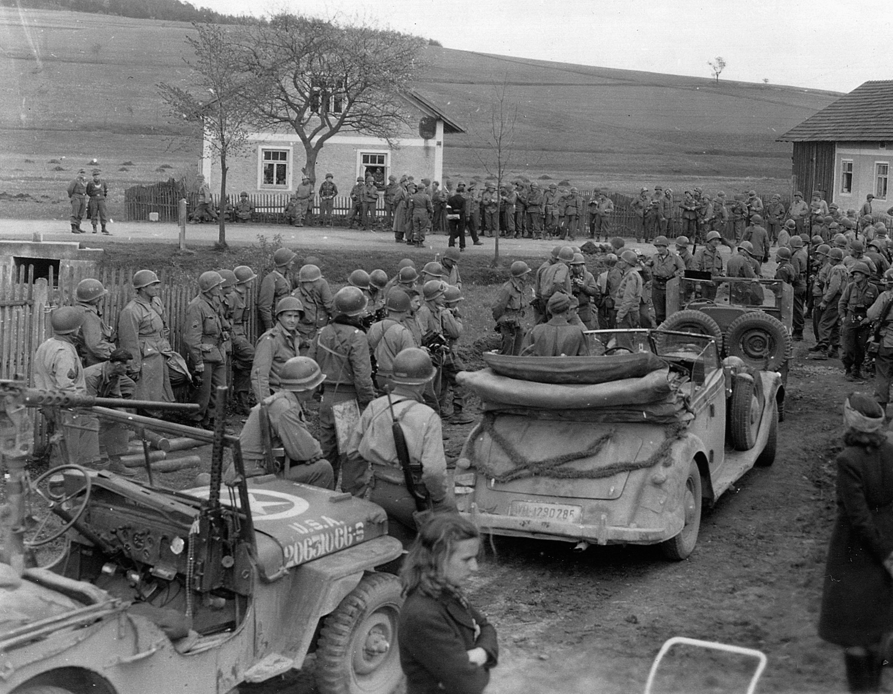 A crowd of 90th and 2nd Infantry Division troops gather as the German 11th Panzer Division makes its formal surrender in May 1945.