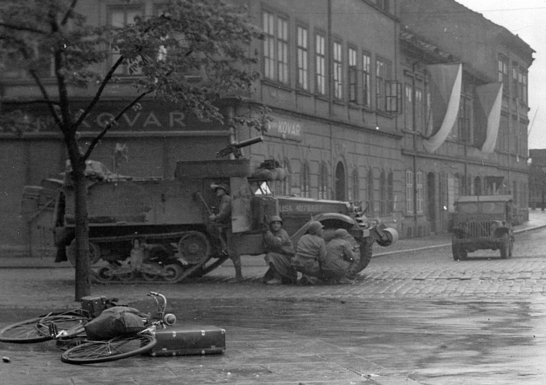 Rolling through a Czech city, U.S. infantrymen quickly take cover as their halftrack comes under the attack of Wehrmacht snipers.