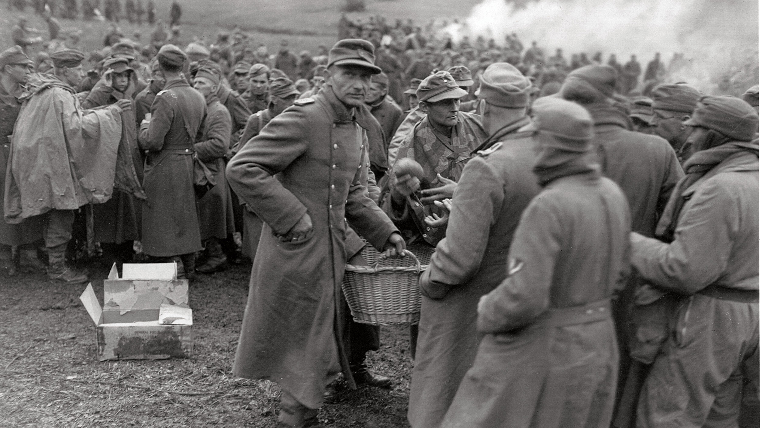 Shortly after a surrender to U.S. forces, German officers hand out rations of bread to hungry soldiers.