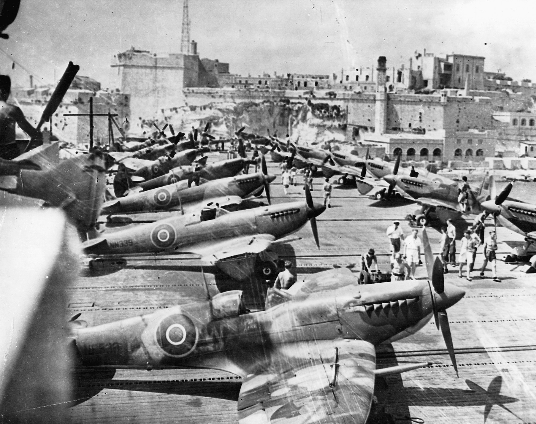 Rows of British Spitfire III’s sit aboard a carrier anchored at Malta.