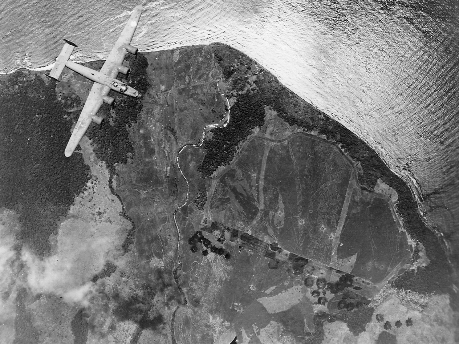 A B-24 of the 5th Airforce flies over the Japanese airfield at Cape Cloucher, New Britain.