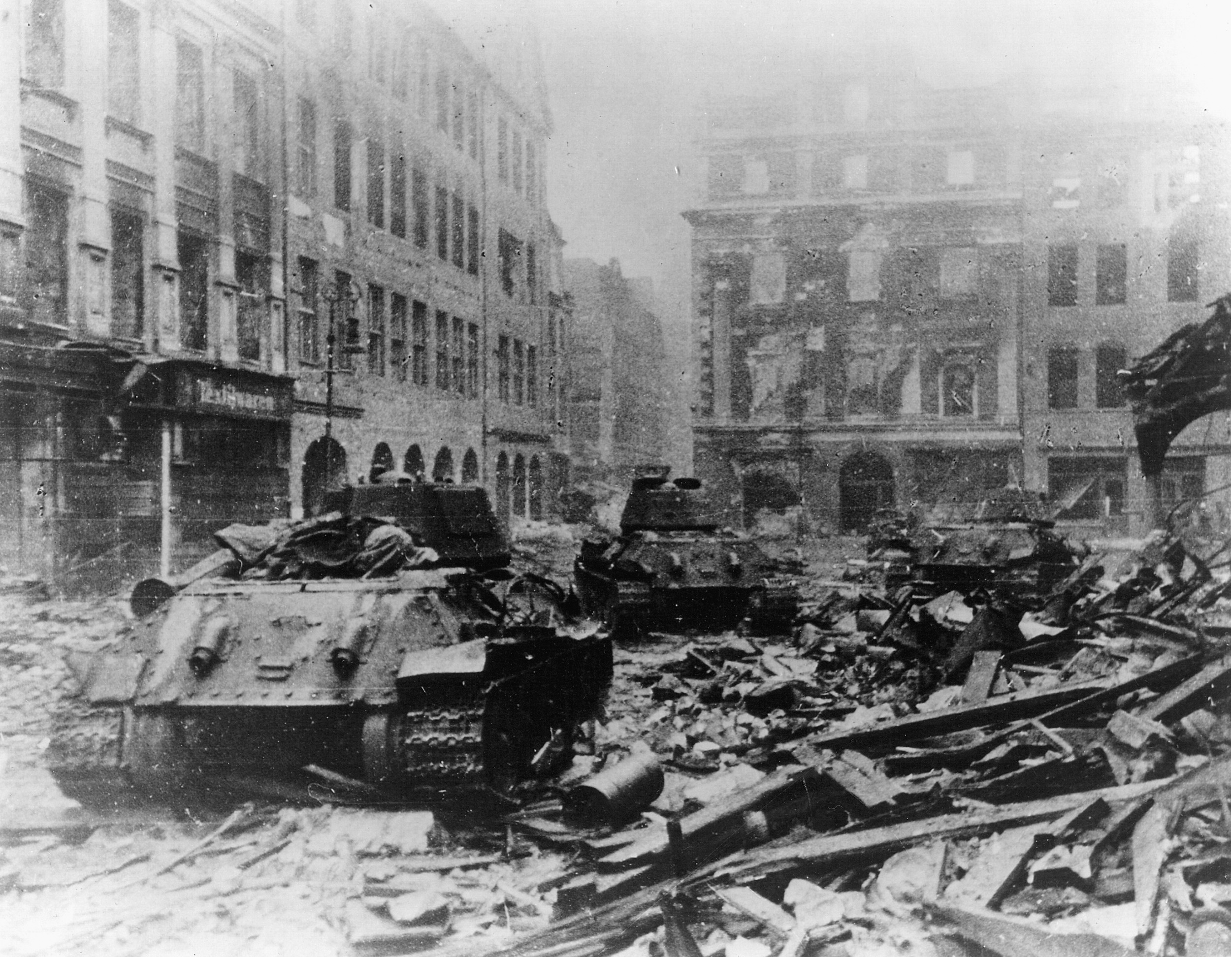 Soviet T-34 tanks rumble through the rubble-strewn streets of Berlin in May 1945.