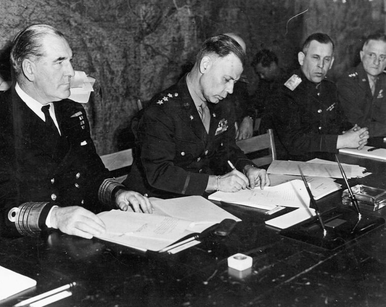 Lt. Gen. Walter Bedell Smith signs surrender papers for General Dwight Eisenhower.