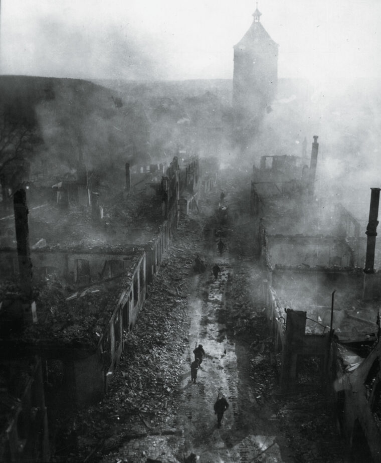 In this eerily surreal image, soldiers of the 225th Infantry Regiment walk down a crowded street in war-torn Waldenburg, Germany. During the final weeks of the war, Allied troops saw firsthand the devastation their war machine had visited upon the enemy.