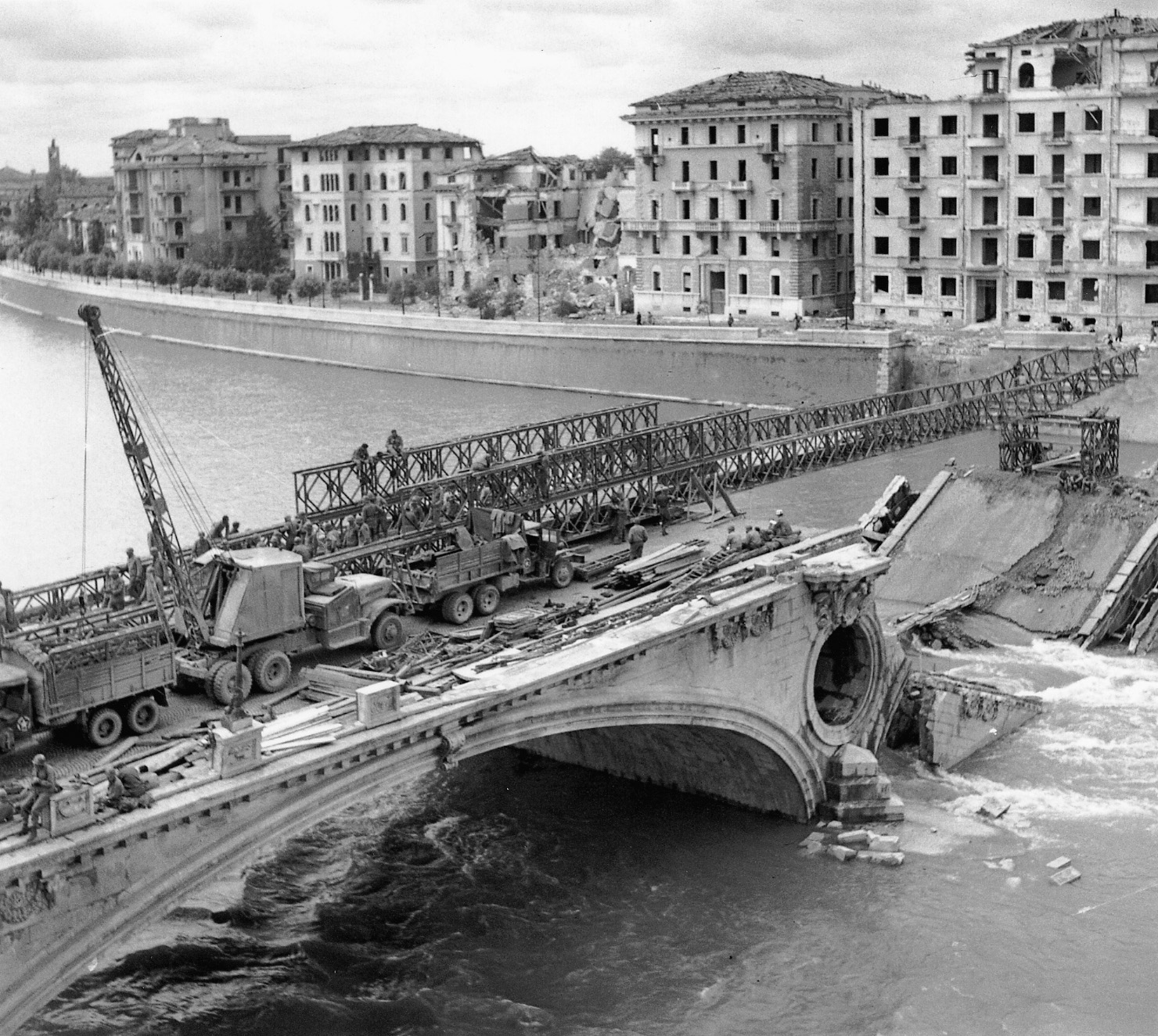 A Bailey bridge is used to re-connect sections of a damaged stone bridge over the River Po in 1945.