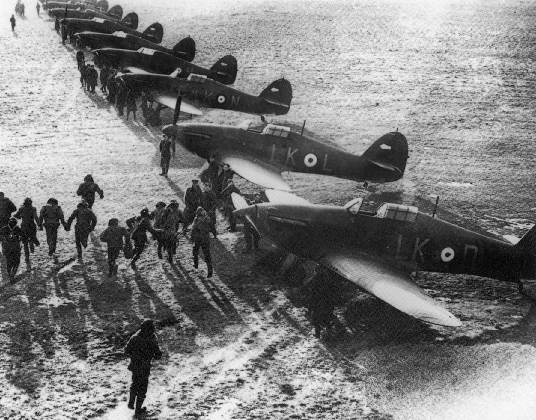 RAF pilots scramble to their Hawker Hurricane fighters to defend the skies over England. Much of the Hurricane was covered with fabric, rather than metal, making it easier to build and easier for ground crews to repair.