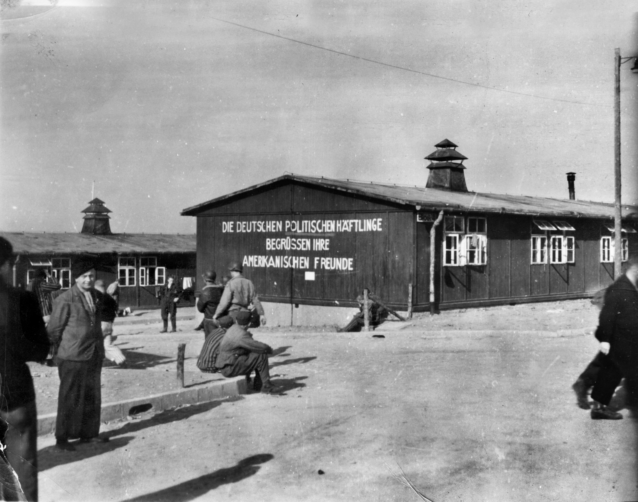  After the first American troops entered the Buchenwald concentration camp near Weimar, Germany, on April 11, 1945, General Eisenhower insisted that as many units as possible visit the camp. Here, two U.S. soldiers walk among liberated prisoners. The sign on the barracks wall reads, “The German Political Prisoners Greet Their American Friends.” 