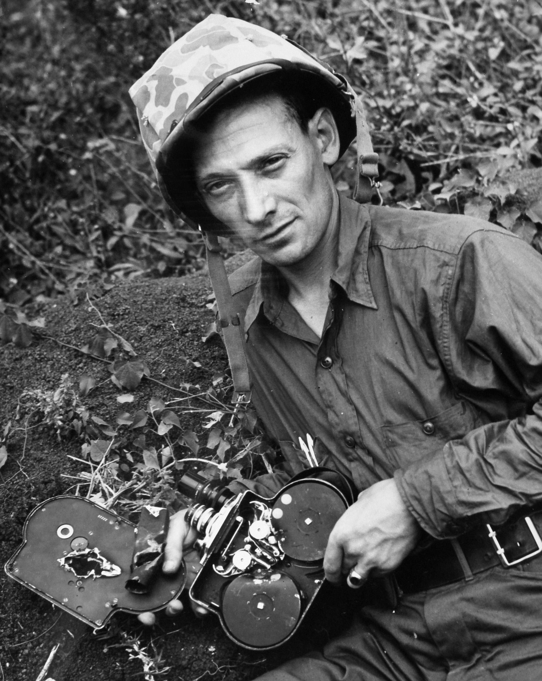 Coast Guard cinematographer Charles W. Bossert shows off the damage to his Bell & Howell Eyemo 35mm movie camera caused by shrapnel from a Japanese mortar on Iwo Jima. Many combat photographers were killed or wounded while trying to get “the shot” and visually document the war.