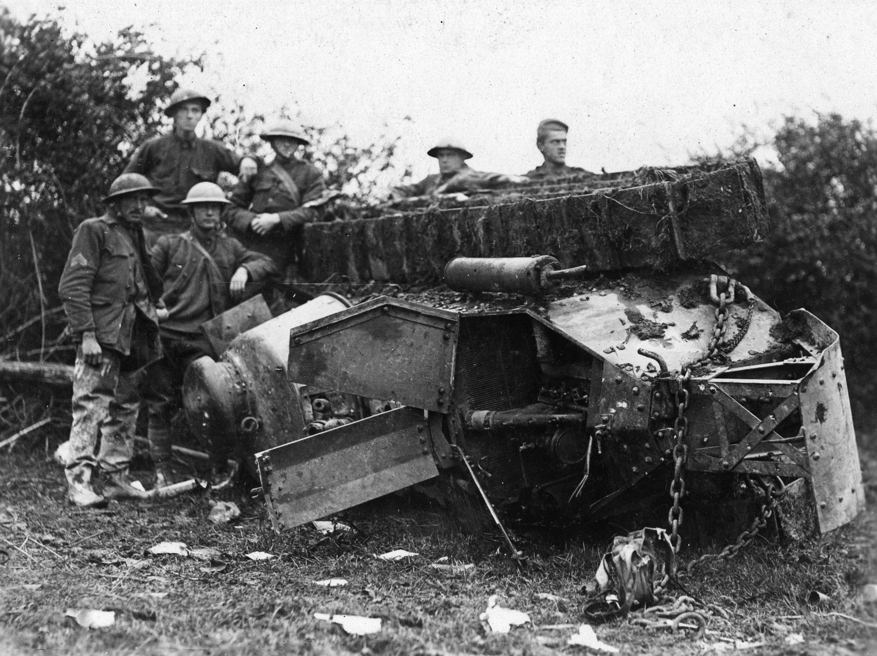 Battle-tested doughboys gather around a French tank overturned by an enemy shell near Cierges. 