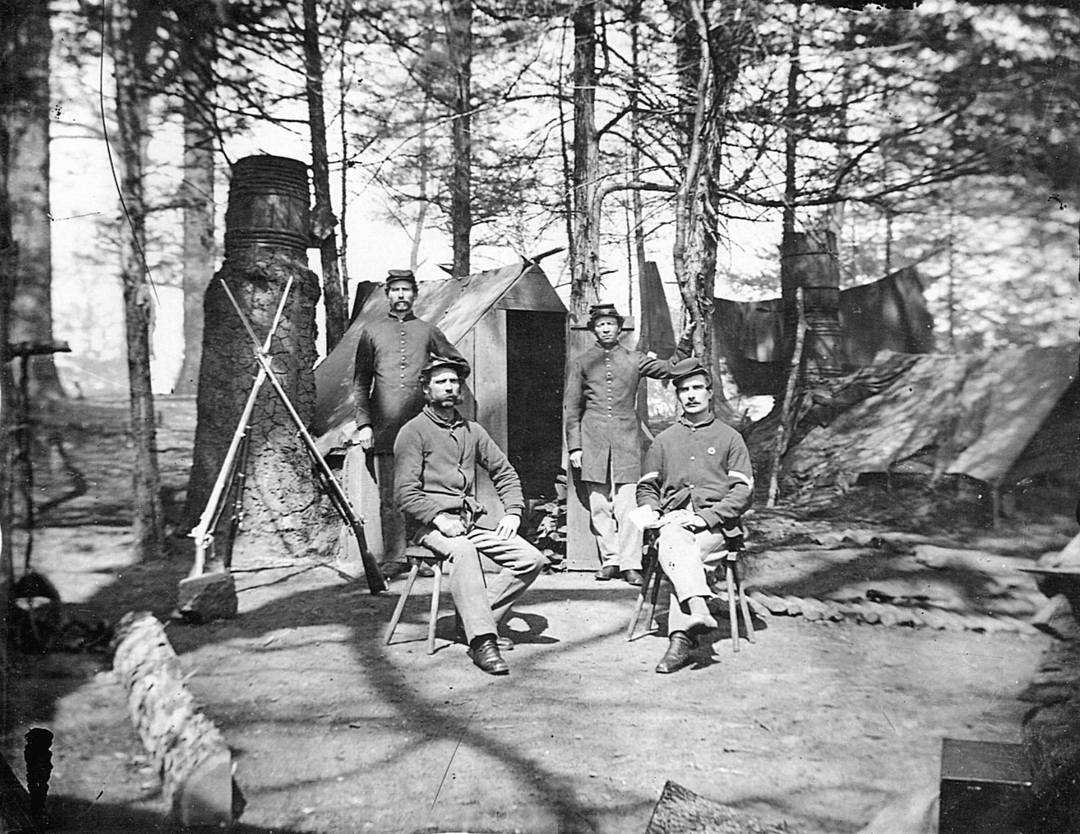 Billy Yanks pose proudly in front of their rudimentary huts. Note the barrels used as chimneys and the log path used to avoid mud during heavy rains.