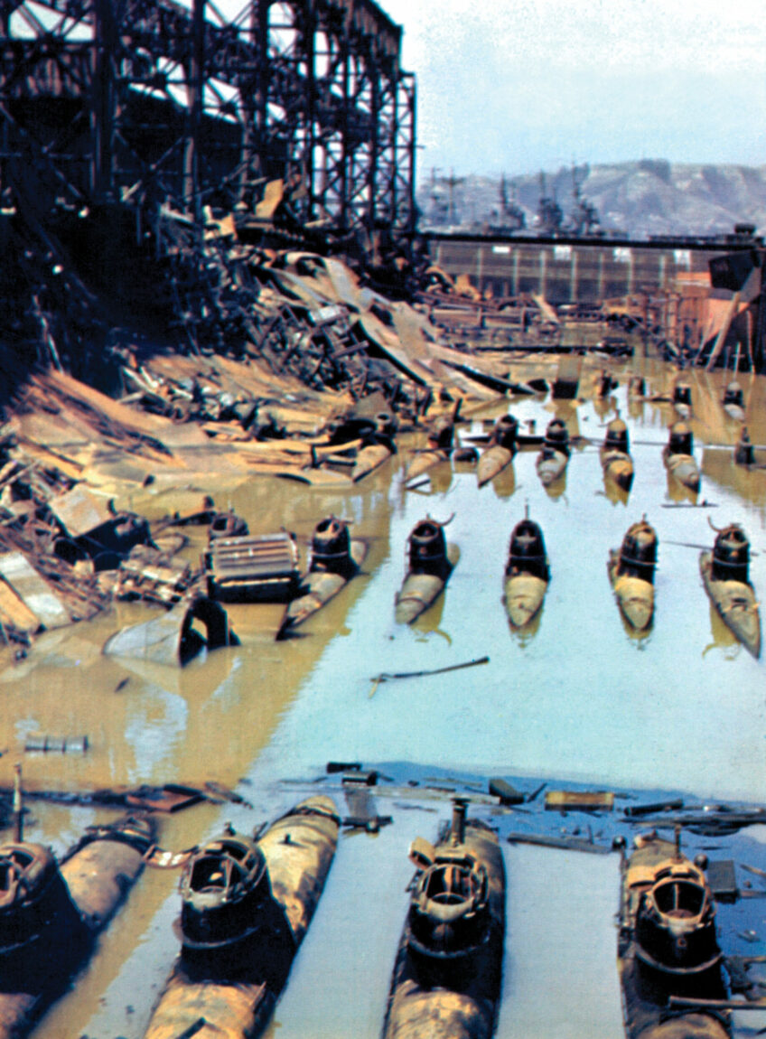Photographed after an American air raid, Japanese midget submarines lie on the muddy bottom of their drydock in the harbor of Kure, Japan. Submarines like these participated in the daring raid against Sydney Harbor in May 1942 and in the attack on Pearl Harbor that plunged the United States into World War II.