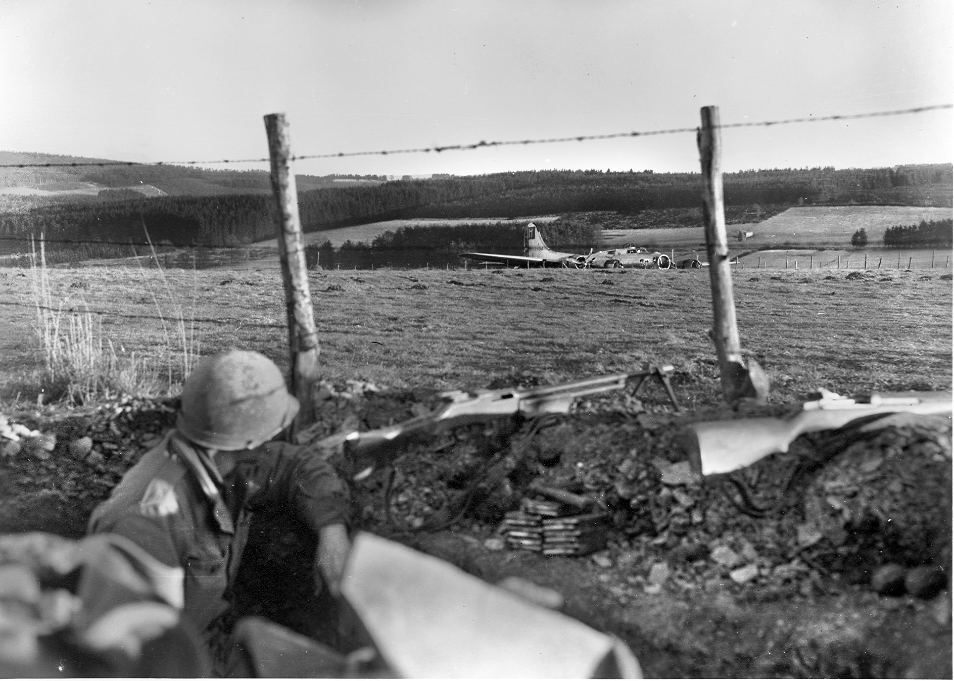 Emil Edgren shot this image of an American GI with a Browning Automatic Rifle looking at a B-17 that crash-landed in a Belgian field.