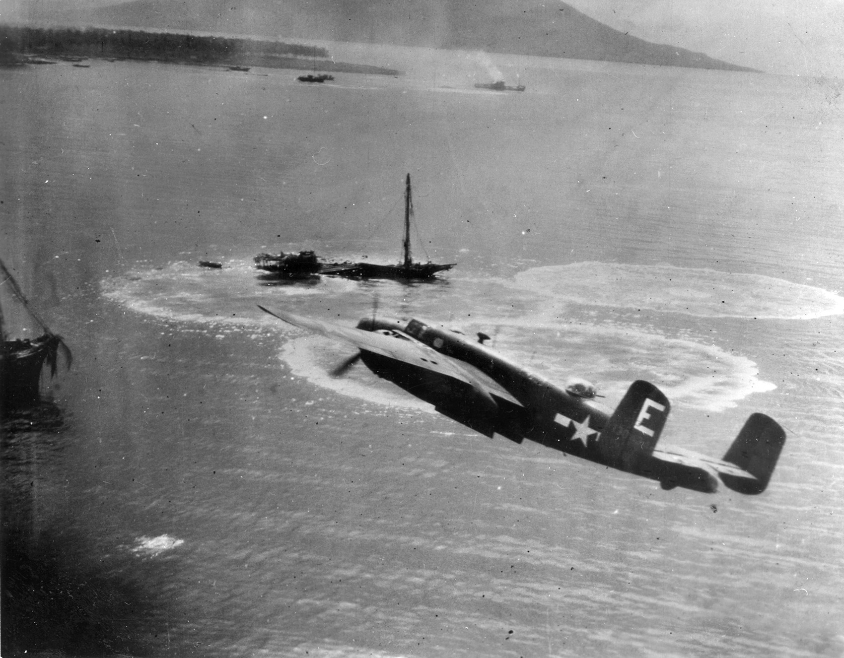 A B-25 Mitchell medium bomber banks toward a stricken Japanese vessel that is already sinking as lifeboats are visible pulling away. B-25s conducted numerous raids on Japanese shipping and shore installations in the South Pacific, often with spectacular results.