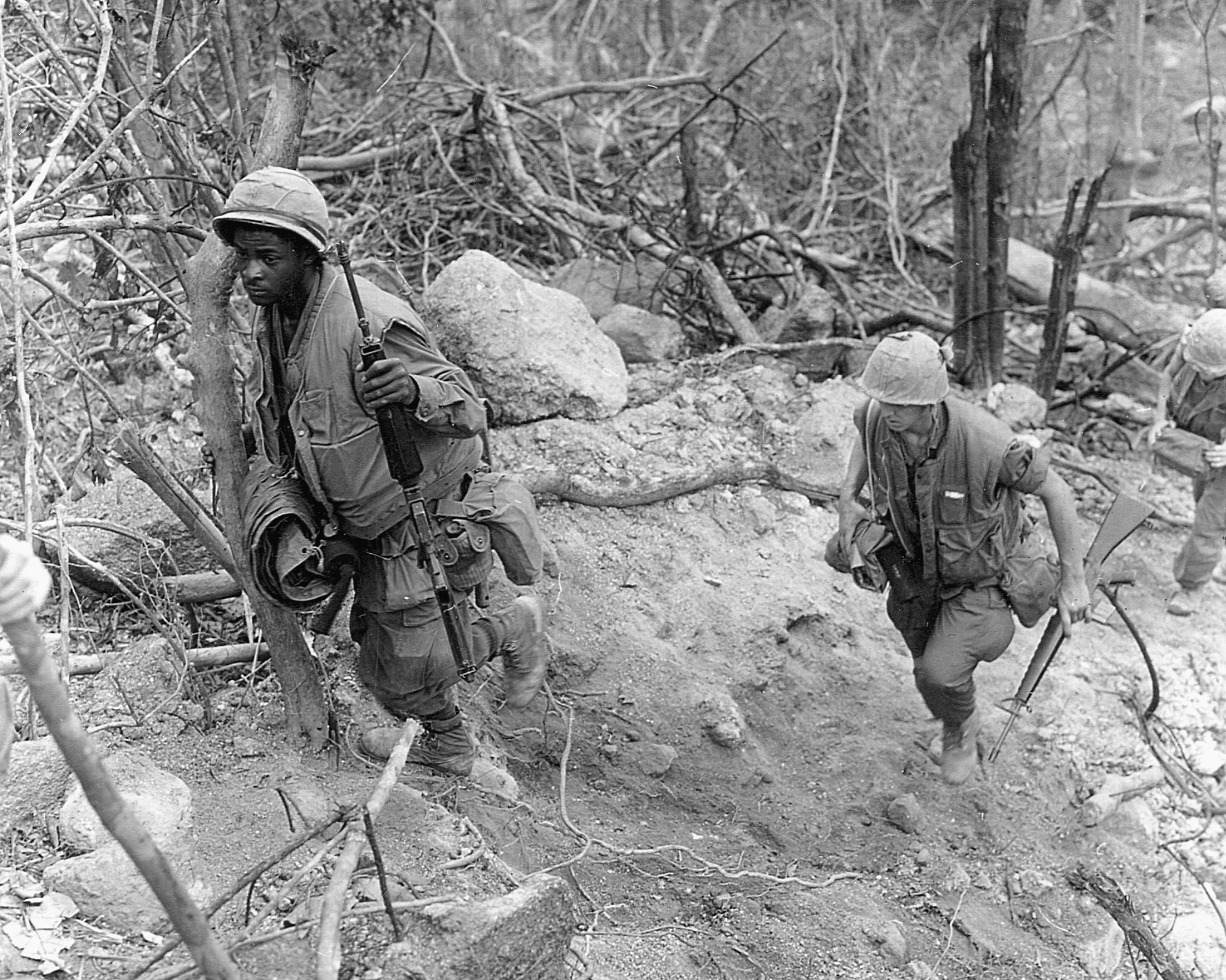 U.S. Marines advance up a barren hillside while searching the area for NVA troops and weapons.