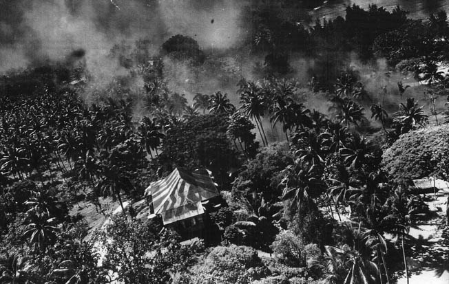 Smoke rises from the heavy jungle of New Ireland and from just offshore in this image of Japanese installations under attack by American B-25 medium bombers at Kavieng harbor on February 15.