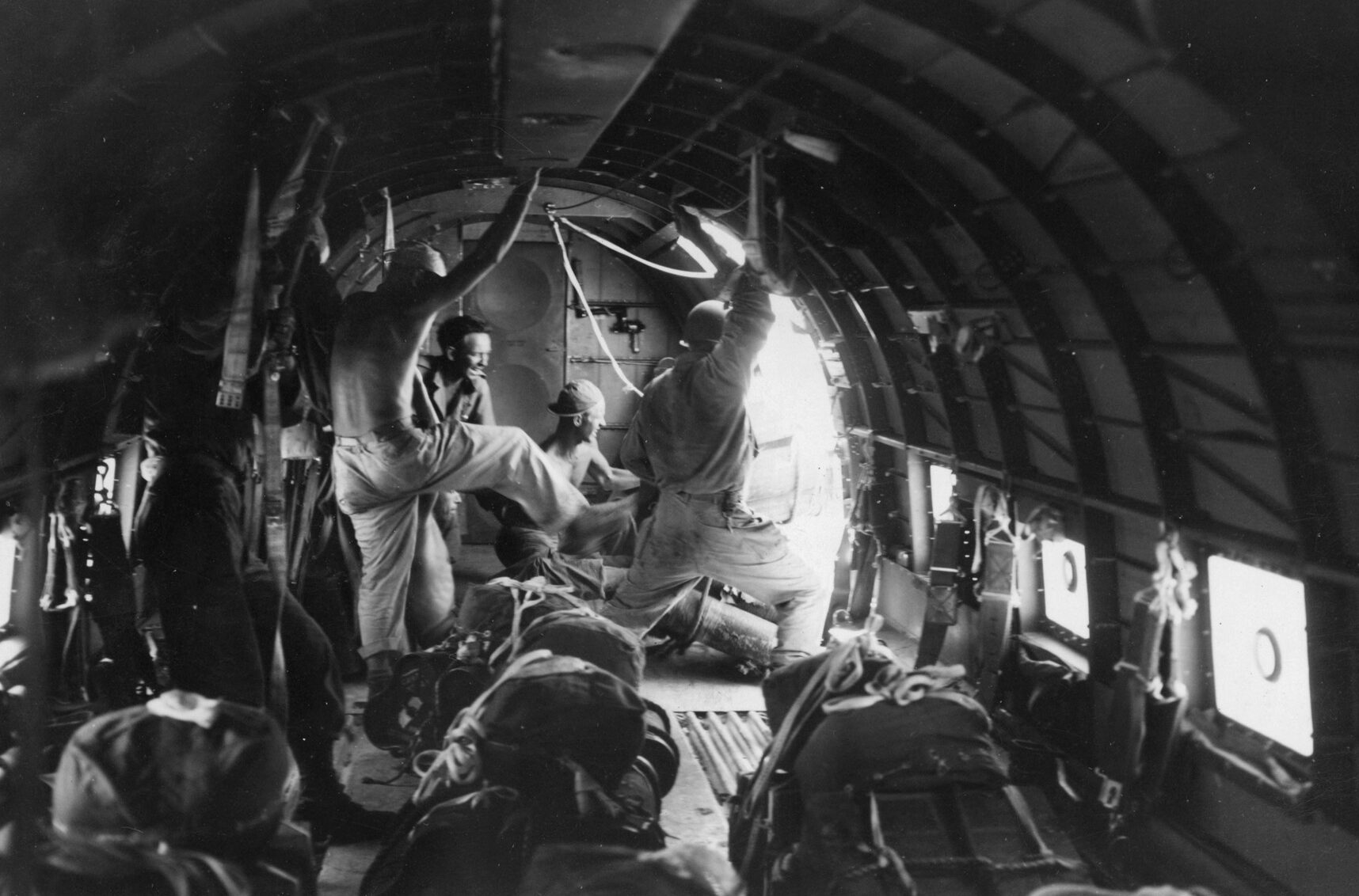 An American airman kicks a packet of supplies out the cargo door of a transport aircraft during the 38th Division offensive on the Bataan Peninsula. The difficult terrain required resupply by air, particularly during the struggle for control of Zig Zag Pass.