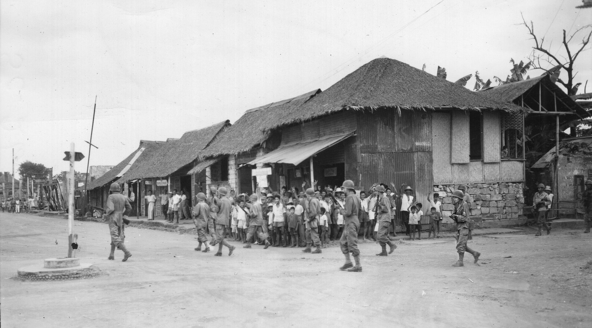 The townspeople of Balanga on the Bataan Peninsula turn out to greet soldiers of the 149th Infantry Regiment, 38th Division, steadily advancing against the Japanese. The circumstances of this trek, following the route of the infamous Death March of 1942, were quite different from the earlier tragic event that claimed many American and Filipino lives.