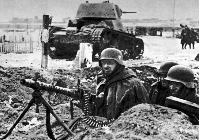 С подбитым советским танком Т-34 за спиной в Демьянске, немецкий пулеметный расчет. Январь 1942 года.