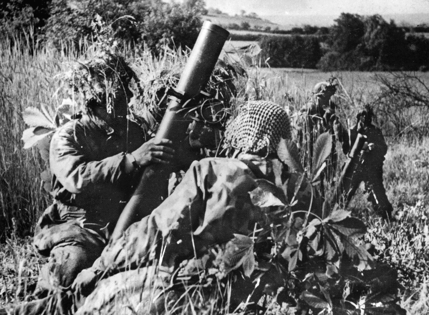 Fighting doggedly on the defensive in the hedgerow country of Normandy, German soldiers fire their 81mm mortars at advancing American troops. Note their heavily camouflaged helmets and uniforms. The Germans were ordered by Hitler to fight to the last man in defense of Cherbourg.