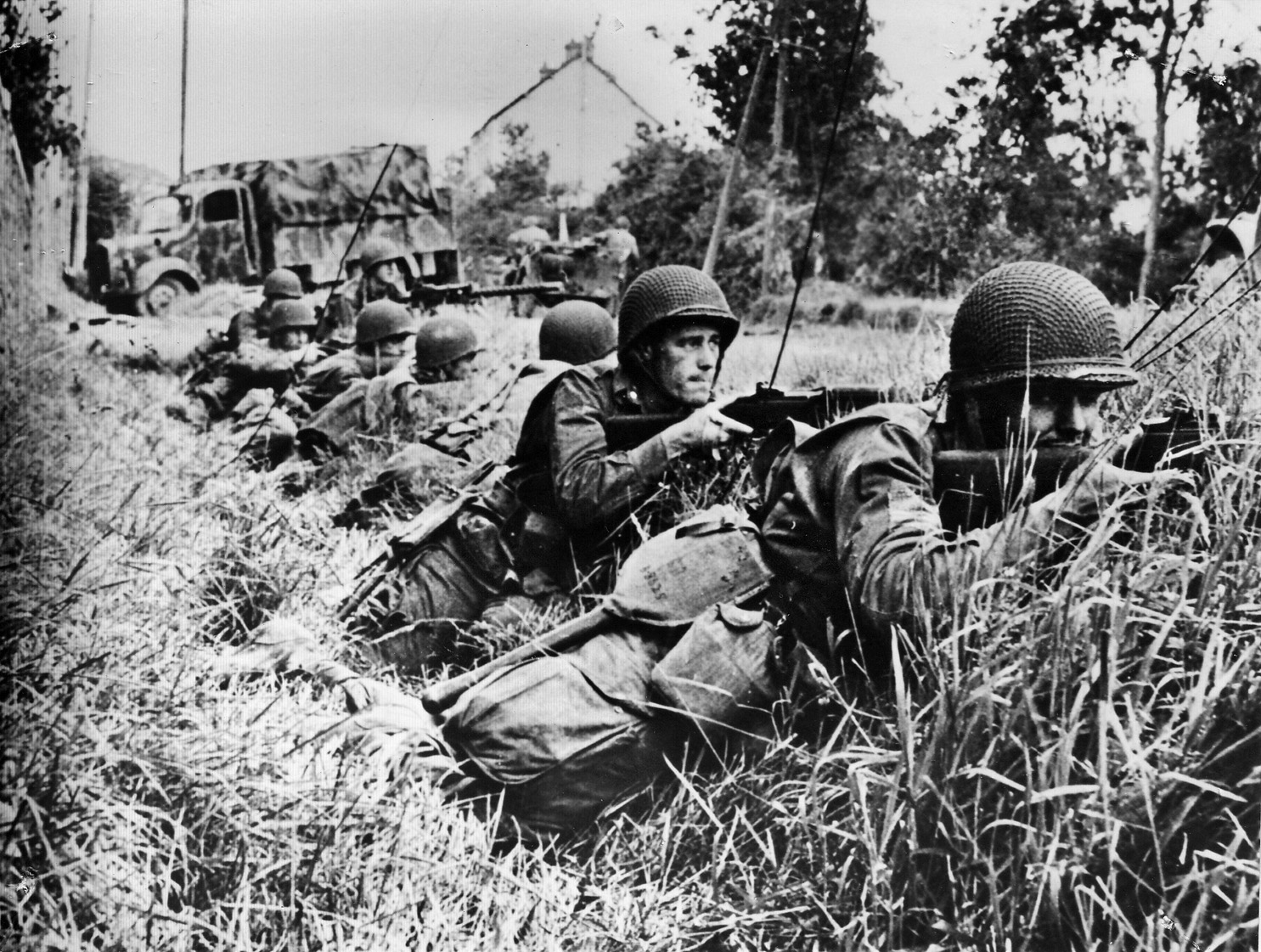 American soldiers return fire against German troops near the town of St. Sauveur, France. The Germans put up a fierce rearguard defense against the advancing Americans, but the town fell on June 16.