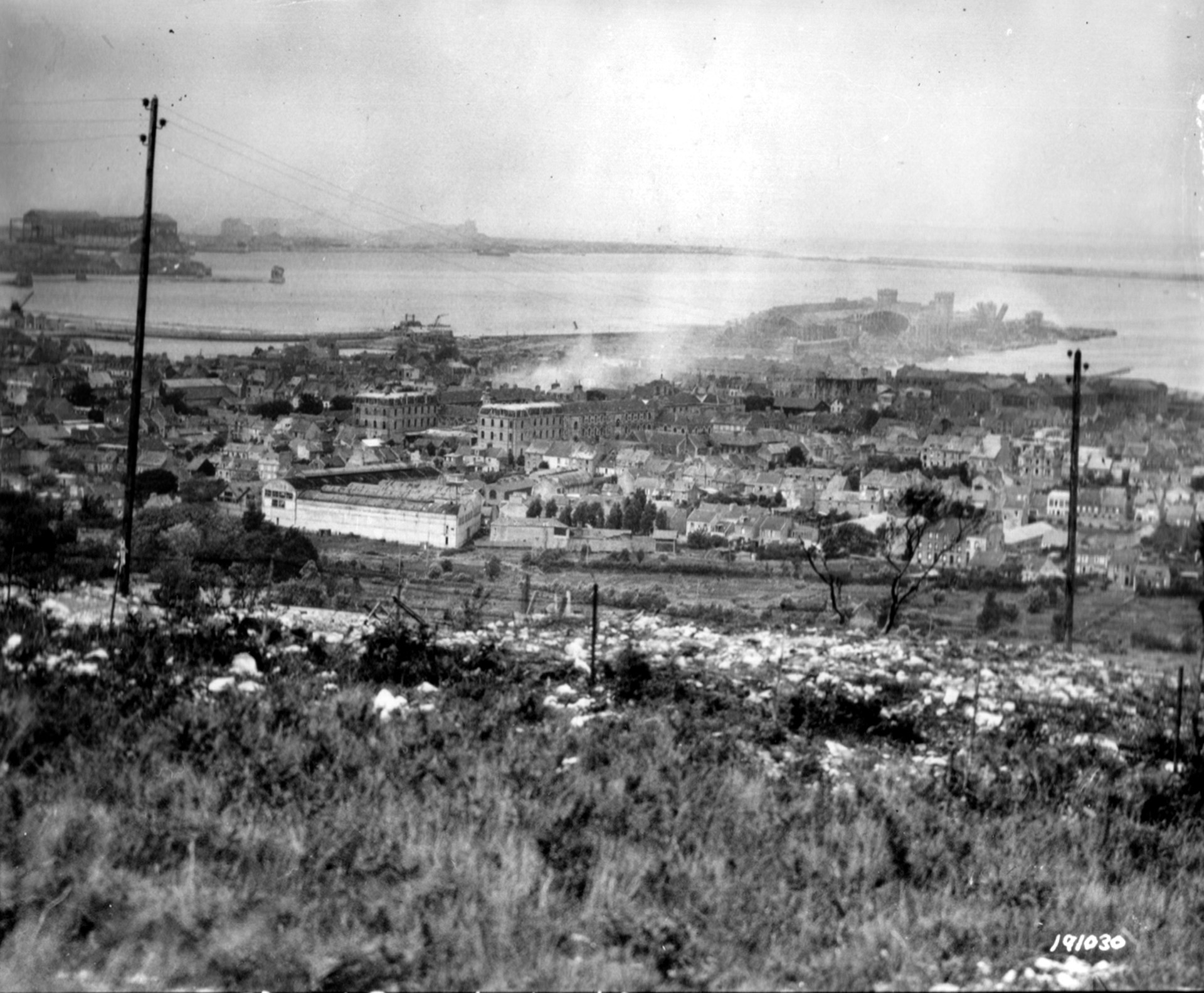 Fort du Roule, a part of the defensive complex occupied by the Germans at Cherbourg, fell to the advancing American soldiers of the 79th Infantry Division on June 26, 1944. In this photo, taken after the fort was captured, the French port city is a smoking ruin with its harbor lying in the distance.