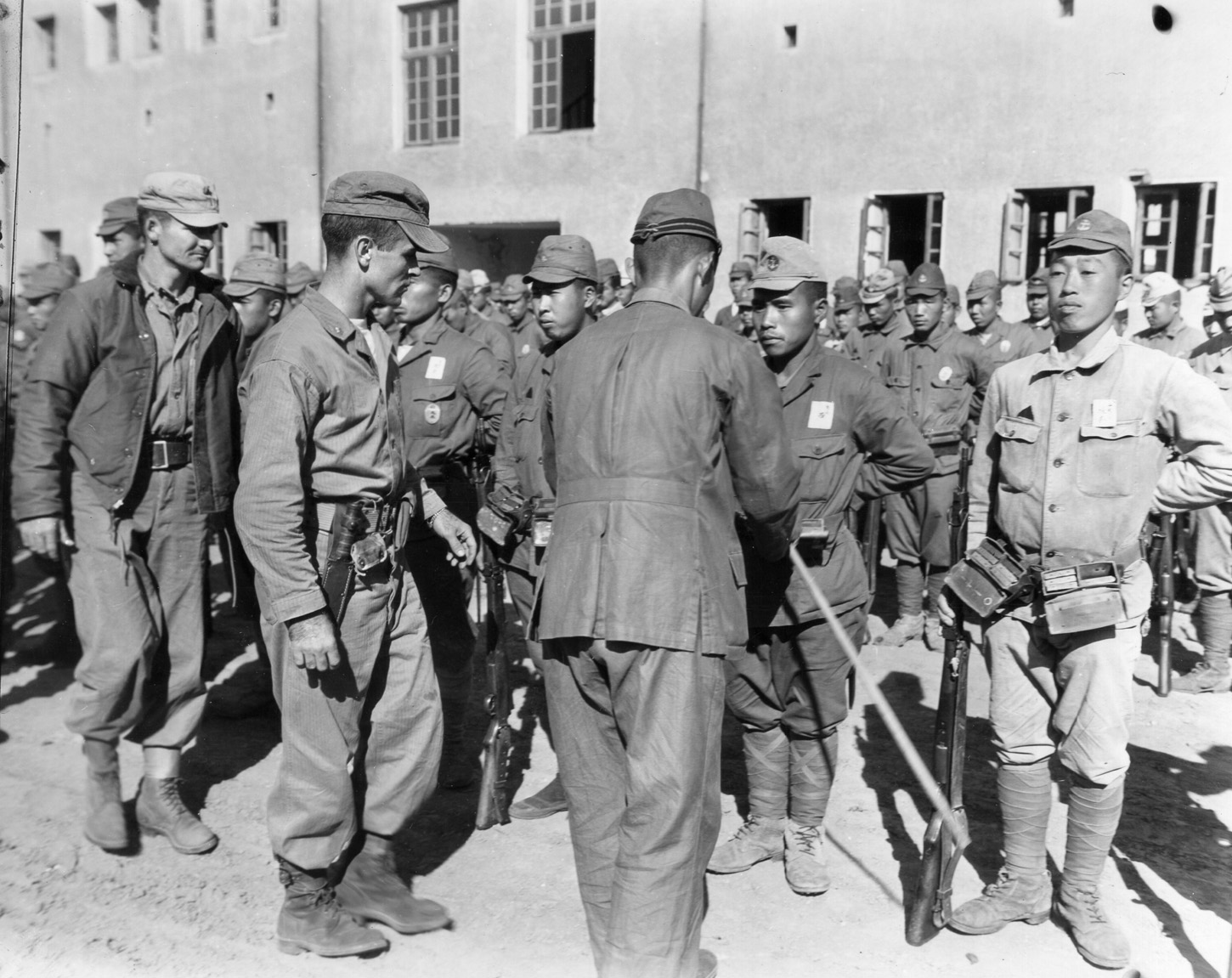 American officers of the 6th Marine Division inspect Japanese soldiers at Tsingtao airfield. As Japanese soldiers were repatriated from China after World War II ended, some remained to guard rail lines against sabotage or disruption caused by the reemergence of civil war in China.