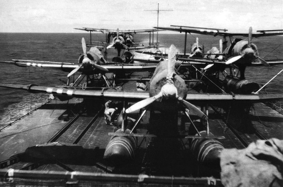 Japanese aircraft are secured to the flight deck that was added to the aft portion of the Mogami in the spring of 1943, following heavy losses in aircraft carriers at the Battle of Midway.