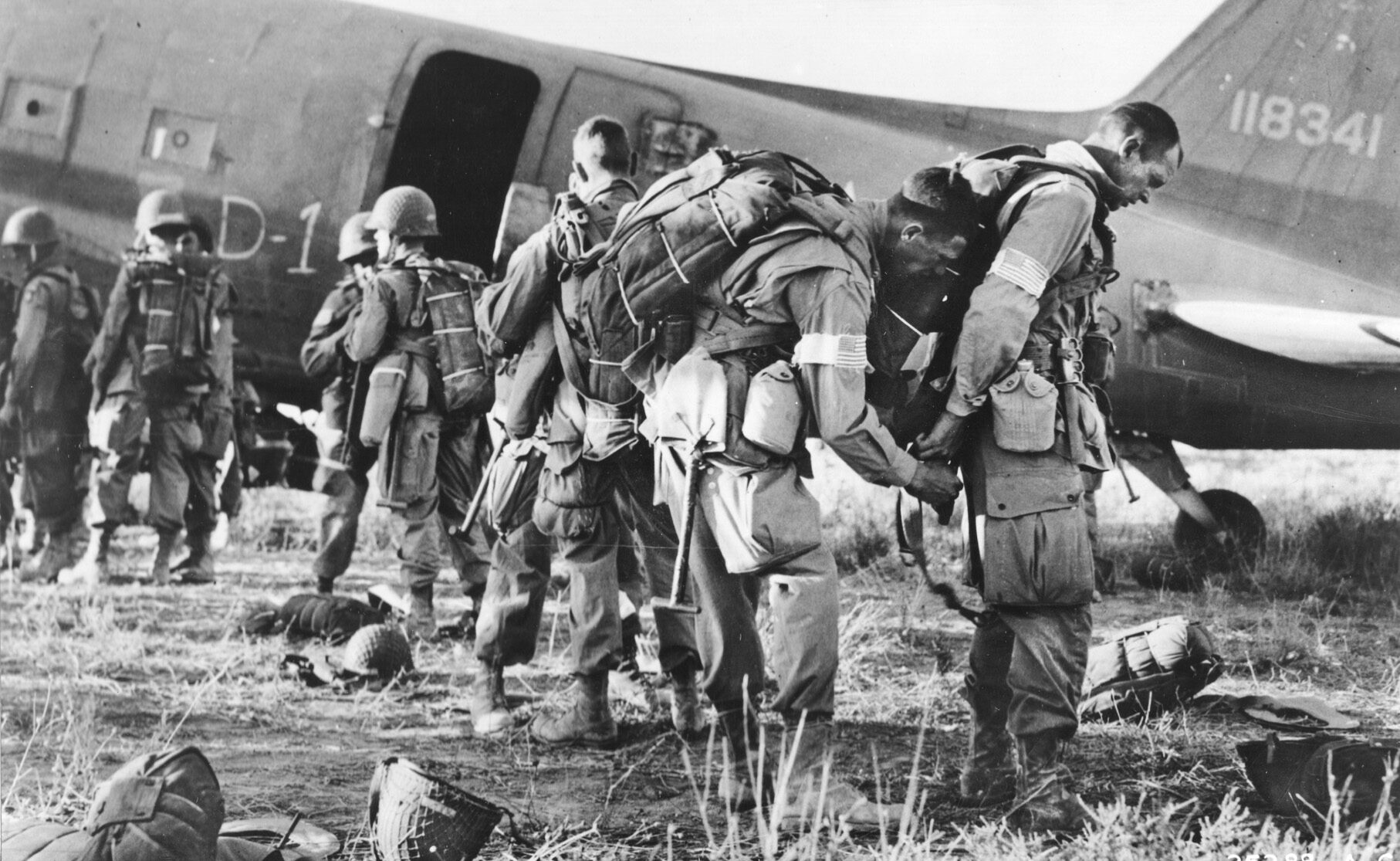 Weighed down by their heavy packs, paratroopers of the 82nd Airborne Division make  last-minute adjustments to their loads prior to boarding transport planes that will take them over  drop zones near the beaches of Salerno, Italy. 