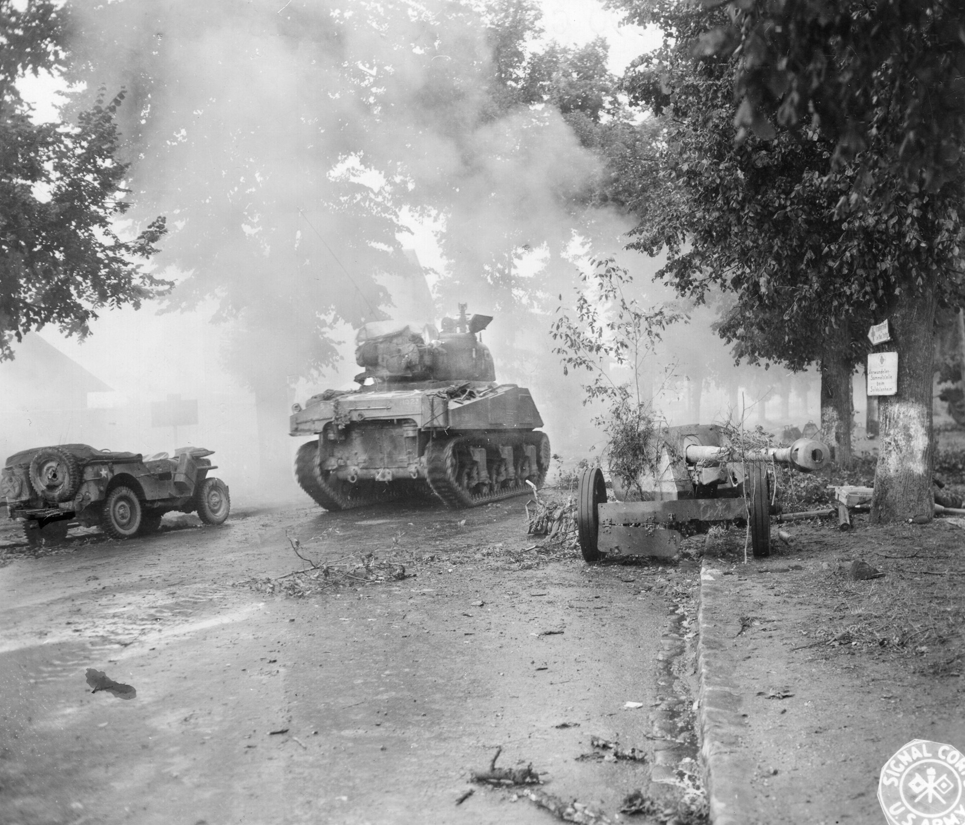 During the American drive to the Seine River in the summer of 1944, an M4 Sherman medium tank drives through the town of Dreux. An abundance of wrecked German vehicles lies in the foreground and down the road.
