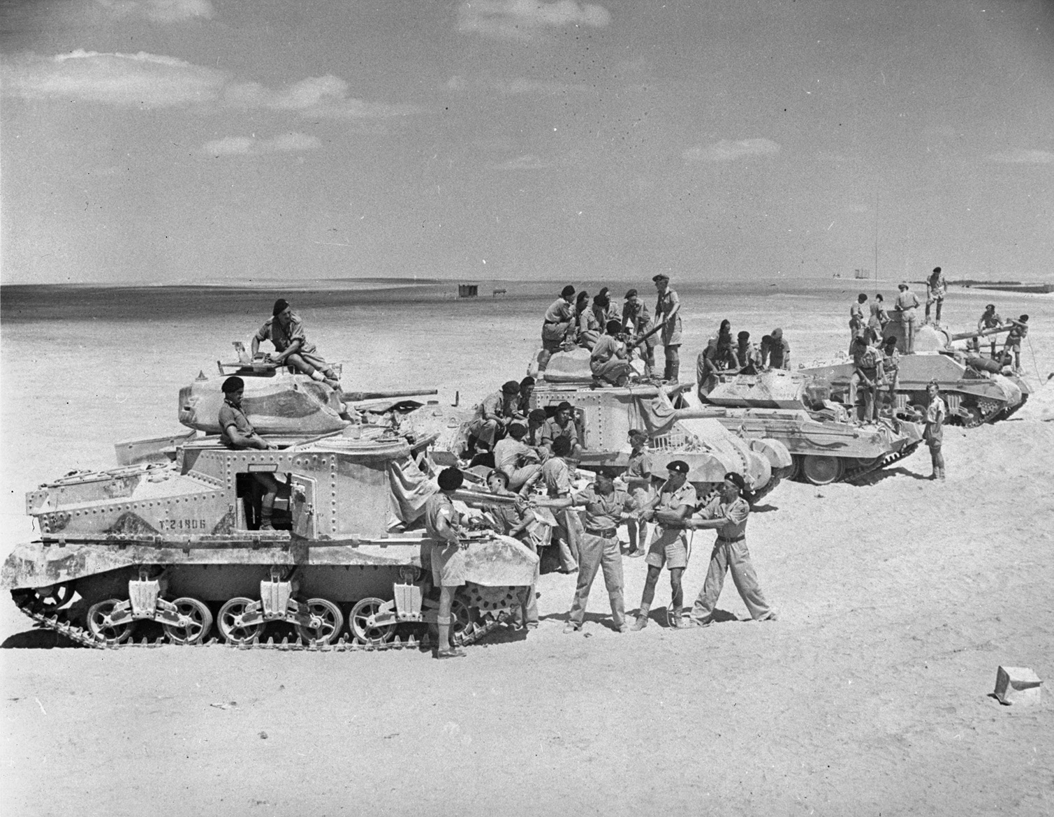 While waiting anxiously for a further combat role, troops of the 6th South African Armoured Division train in the Middle East sands with Grant, Crusader, and Sherman tanks. 