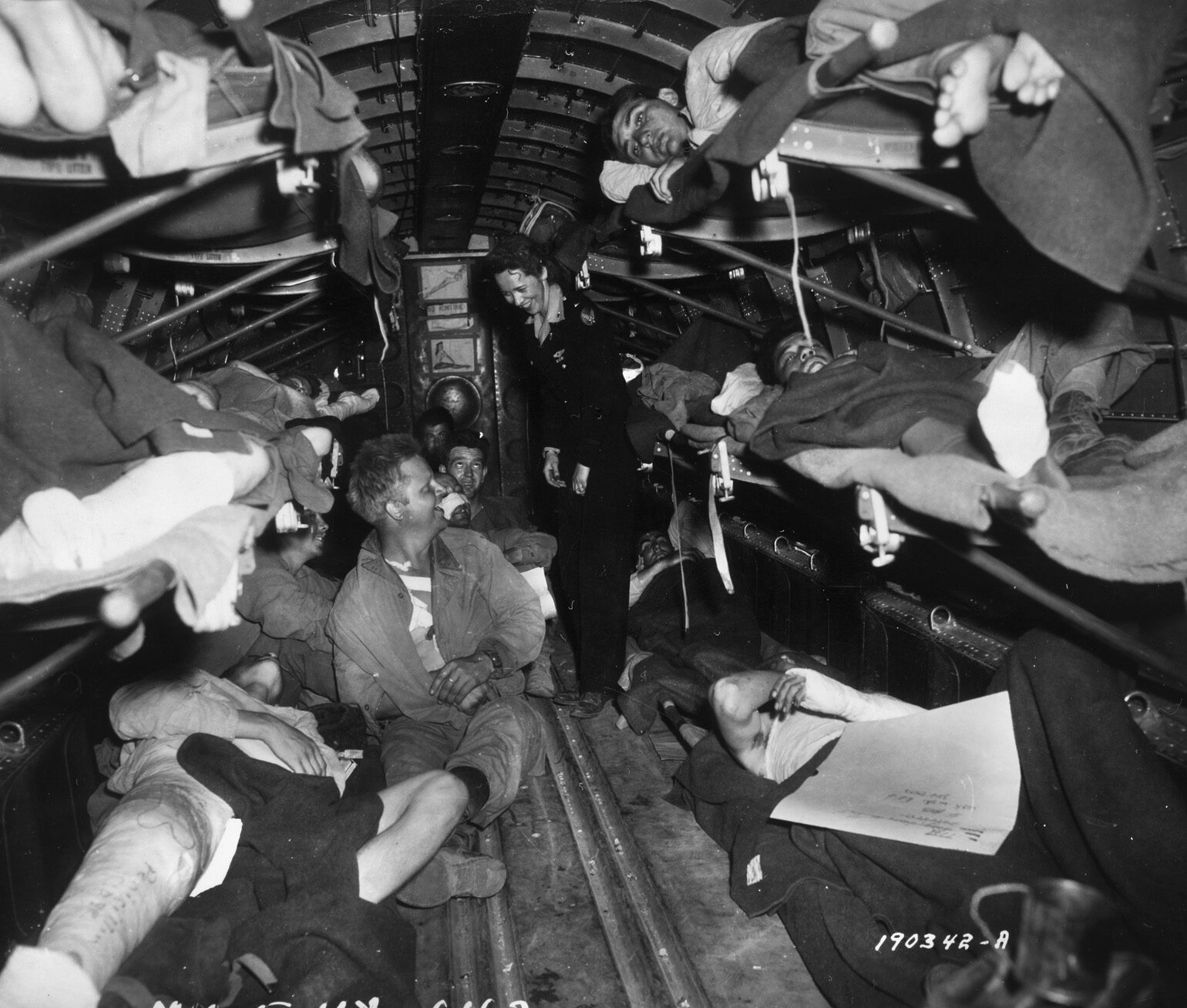 A flight nurse cares for wounded soldiers aboard a C-47 Skytrain transport.