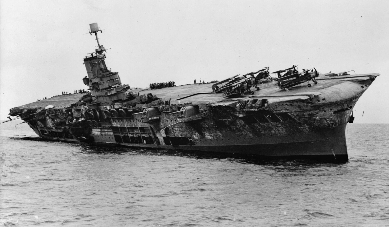 British aircraft carrier HMS Ark Royal lists heavily after being torpedoed off Gibraltar by U-81, November 13, 1941, necessitating American carriers to ferry aircraft to Malta in 1942.