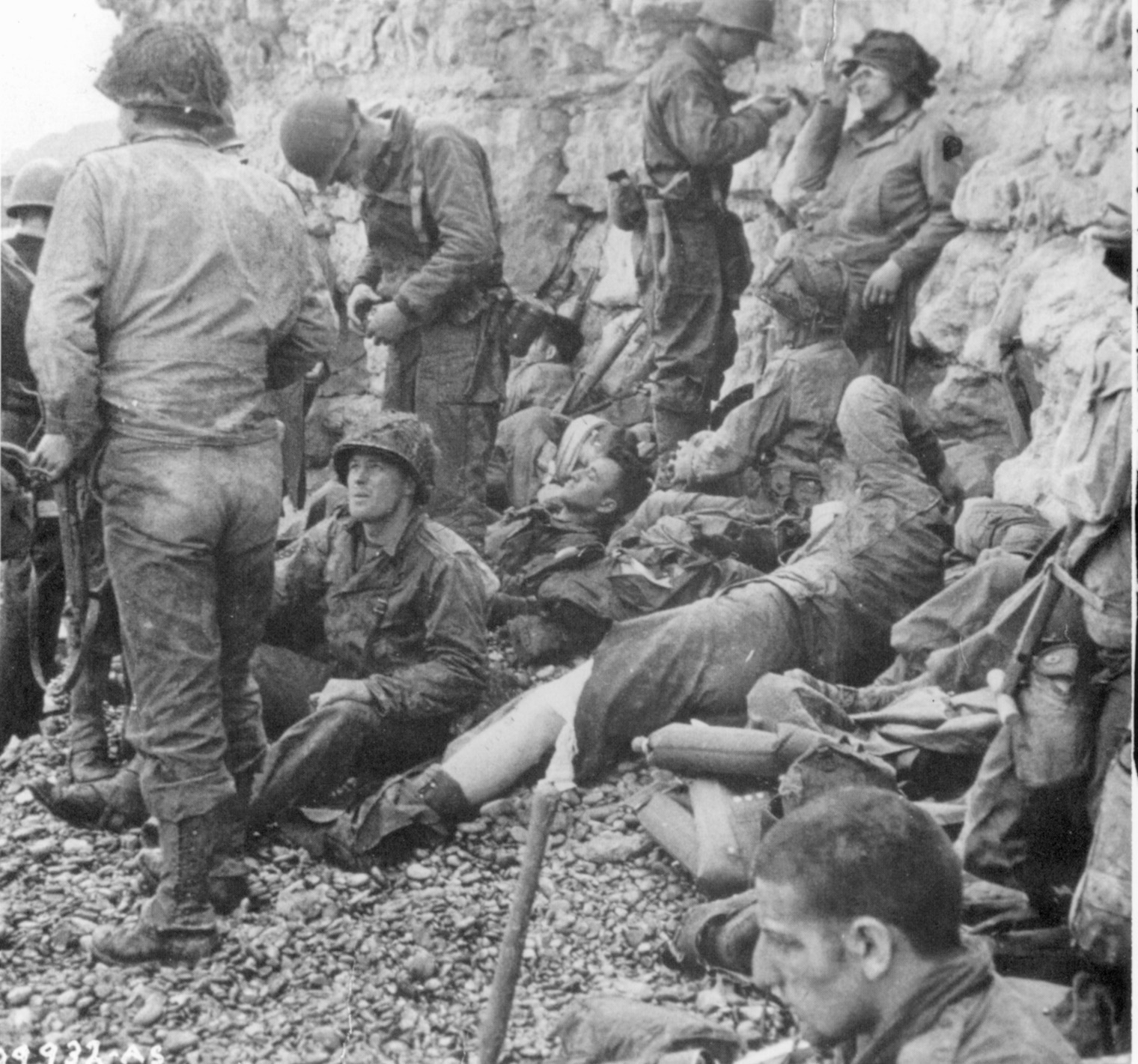 Sheltering against a cliff at the edge of Omaha Beach, members of Company L, 16th Regiment prepare to assault German positions.