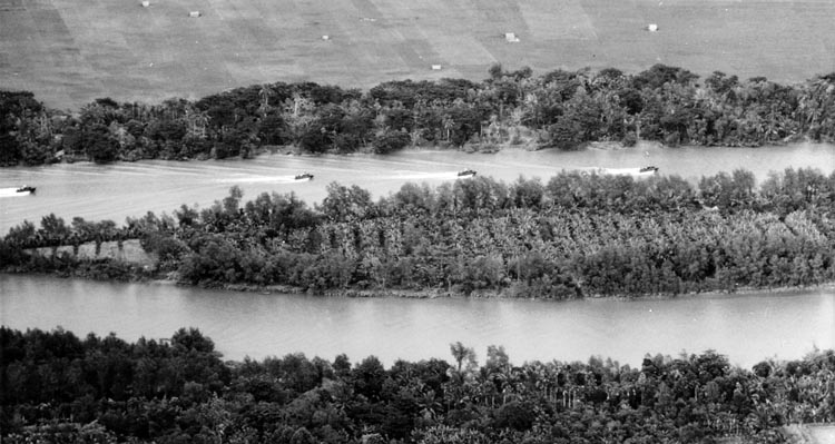 Navy PBR boats cruise past Tan Dinh Island, trying to draw fire from enemy fortifications along the river bank. Once the boat crews had pinpointed the enemy positions, helicopter gunships would attack the strongpoints from overhead.