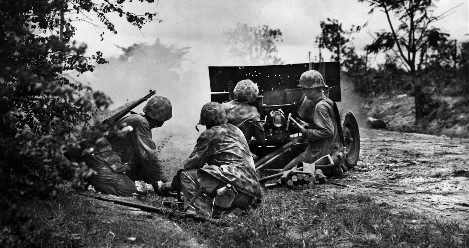  The crew of a 37mm light field gun, its shield perforated by numerous bullet holes, fires at Japanese positions near Garapan.