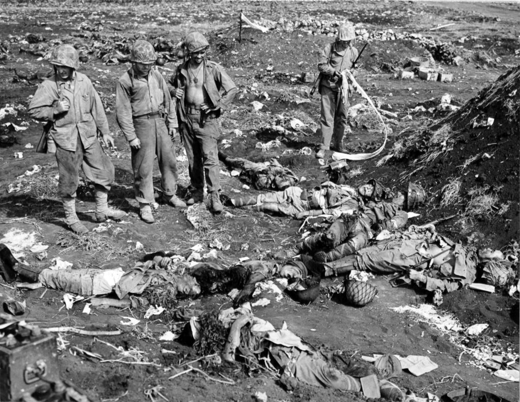 A group of Marines survey the corpse-strewn battlefield. Most Japanese soldiers, believing that surrender was dishonor, preferred to die fighting or commit suicide rather than be taken prisoner. 