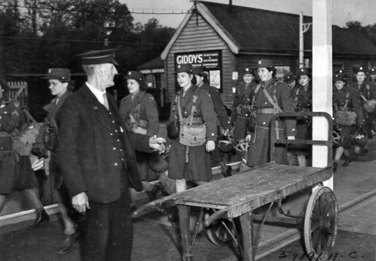 A British railway conductor looks on as a group of WACs arrives at Ninth Air Force headquarters in Sunninghill, Berkshire, England, May 1944.