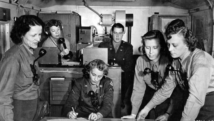 WACs in a mobile control unit truck provide directional information to the crew of a damaged U.S. bomber returning from a mission over Germany. The WACs standing at left and right are plotting the aircraft’s course. OPPOSITE: Navy WAVES make repairs to the port outboard engine of a Douglas R5D four engine transport 
