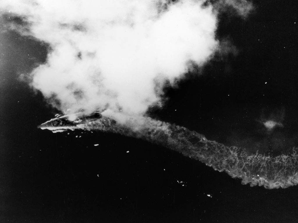  The Yamato maneuvers hard to port to avoid incoming American aircraft. Although fire can be seen amidships from previous attacks, the mighty ship has not yet begun to list.