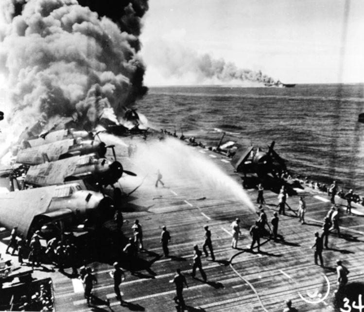 Crewmen aboard the carrier USS Belleau Wood off the Philippines pour water on aircraft and burning flight deck after a Kamikaze strike, October 30, 1944. The carrier <a href=