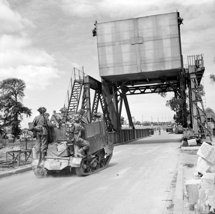 A heavily laden British Universal Carrier heads east across the Bénouville Orne Canal bridge, now known as Pegasus Bridge in honor of the Pegasus insignia