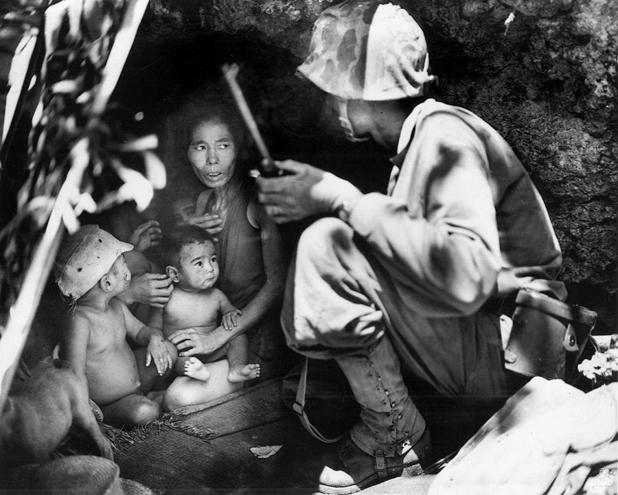 A U.S. Marine tries to convince a wary civilian family, hiding in a cave, that they won’t be harmed if they come out. Many others, however, believed Japanese propaganda that the Americans would treat them cruelly and jumped to their deaths from cliffs.
