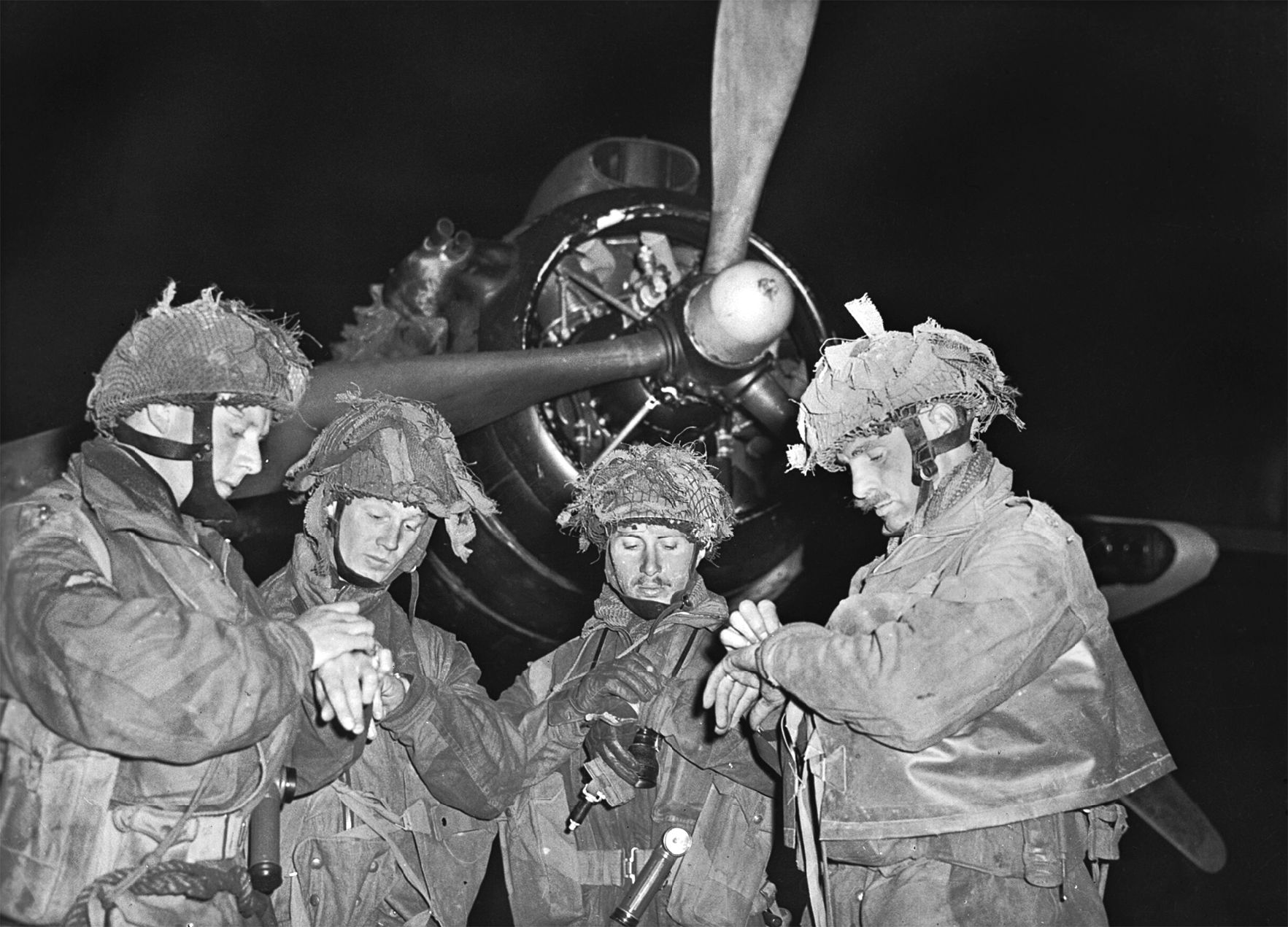 British paratroops synchronize their watches before taking off on their airborne assault mission.