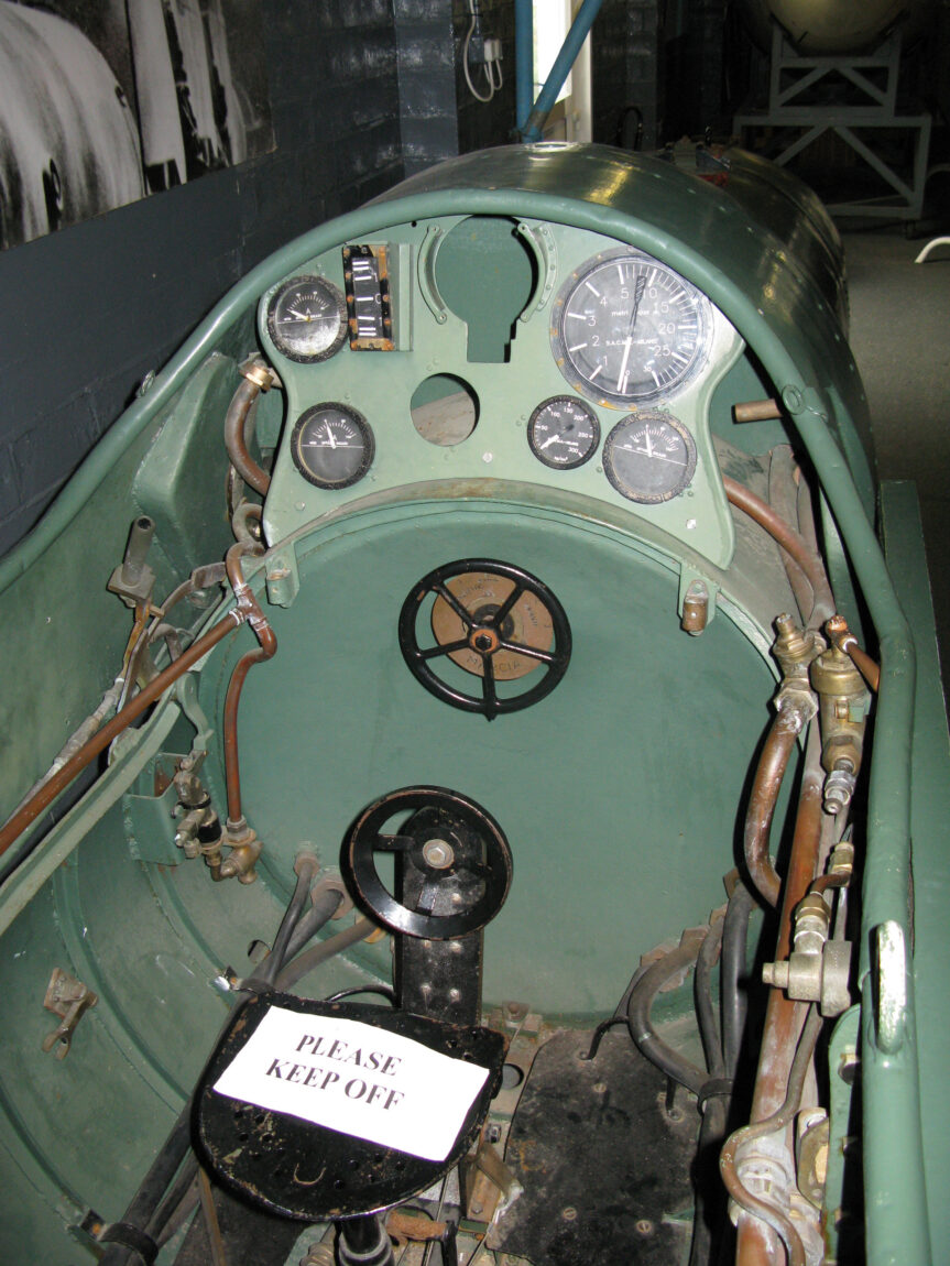 The cramped cockpit of an Italian manned torpedo reveals a few dials and the tiny steering wheel that the driver literally wrestled in order to steer the vessel.